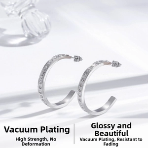 Close-up of silver C-shaped titanium earrings featuring micro-set sparkling crystals