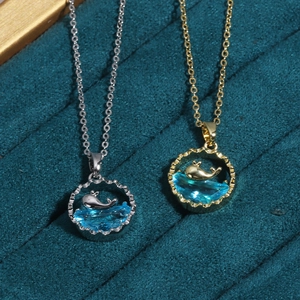 Detailed view of silver and gold whale tail pendants with blue gems on velvet