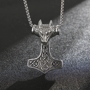 Macro shot of silver punk wolf head and Celtic knot Mjölnir hammer pendant necklace