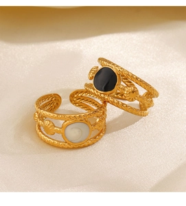 Detail of bohemian gold layered rings with black enamel and white mother of pearl