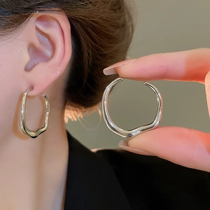 Close-up of minimalist irregular twisted silver earrings worn by a female model