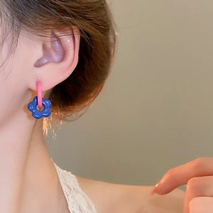 Close-up of asymmetric flower earrings in blue and pink on model for stylish daily wear