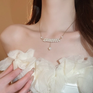 Detail of elegant double-layered faux pearl necklace with gold chain on model neck
