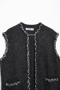 Détail de l'étiquette sur une robe en tweed noir ornée de paillettes argentées et franges