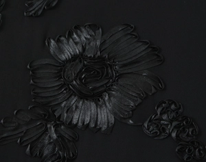 Detailed macro view of 3D floral embroidery on high-quality black fabric texture