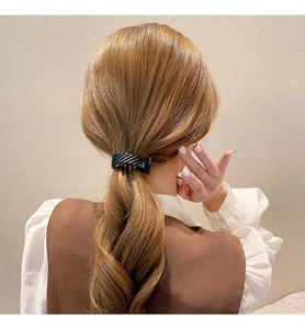 Detail showing matte black resin hair claw clip holding a high ponytail on brown hair