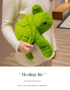 Close-up of a soft green turtle plush pillow with detailed shell texture held in hands