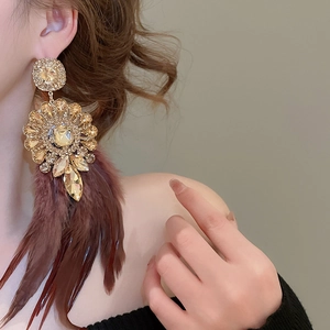 Détail de boucles d'oreilles de luxe avec strass et pompons en plumes marron rouge