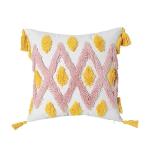 Close-up of tufted geometric embroidery and yellow tassels on white cushion cover