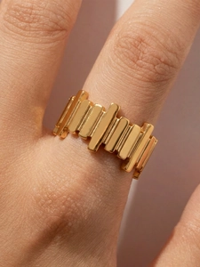 Detailed macro view of an irregular geometric gold striped ring with polished metal finish