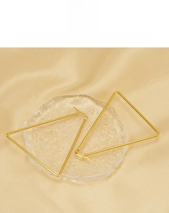Macro shot of geometric gold triangle earrings on a silk background with soft lighting