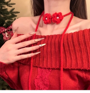 Detail of red knit floral choker with faux pearls paired with matching lace sweater