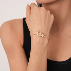 Close-up of golden butterfly and clover cuff bracelet with sparkling zircon stones