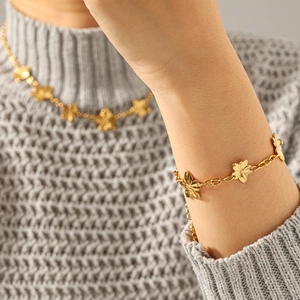Elegant gold five-petal flower jewelry set including necklace and bracelet on a grey sweater