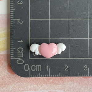 Close-up of pink resin heart with white wings on a grid mat measuring 2.2 cm