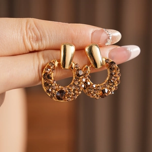 Gros plan de boucles d'oreilles dorées vintage avec zircons champagne et design évidé