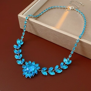 Detail view of a silver heart necklace with blue zircon crystal on a jewelry box