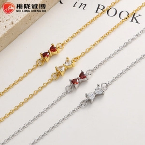 Detail of silver bow bracelets with red and clear heart-shaped zircon stones in gold and silver