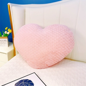 Gros plan du coussin rose en forme de cœur avec texture pelucheuse 3D sur un lit blanc