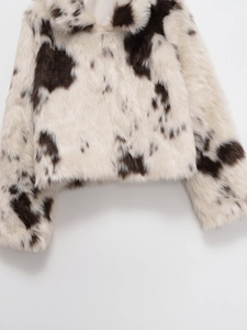 Détail de la texture en fausse fourrure pelucheuse et motif vache noir et blanc de la veste