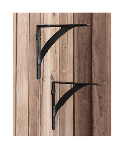 Detail of two black cast iron shelf brackets in rustic industrial style on wood wall
