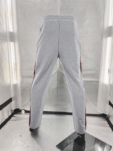 Detail view of grey knit jogger pants with red and black plaid side stripe detail