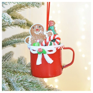 Close-up of a red clay mug ornament with gingerbread man and candy cane on snowy tree