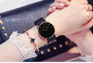 Close-up of Hannah Martin black dial watch paired with a rose gold clover bracelet