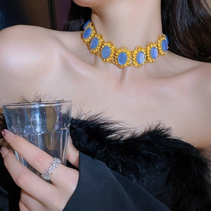 Close-up of vintage gold choker necklace featuring ornate blue oval gemstones