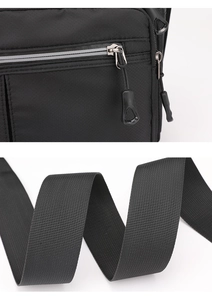 Detail of durable black nylon fabric with silver zipper and wide woven shoulder strap