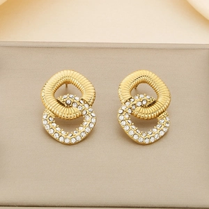 Close-up of gold-plated twisted double hoop earrings with sparkling crystal rhinestones
