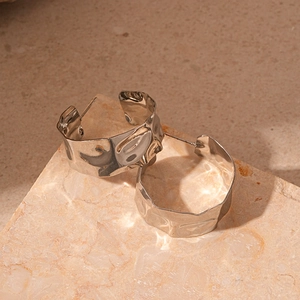 Detailed view of silver hoop earring with hammered metal texture on stone surface