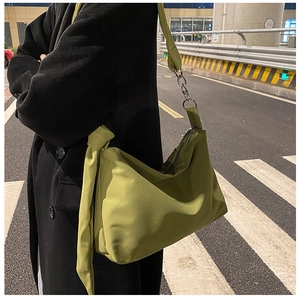 Detail of green nylon shoulder bag featuring knotted strap and silver chain accent