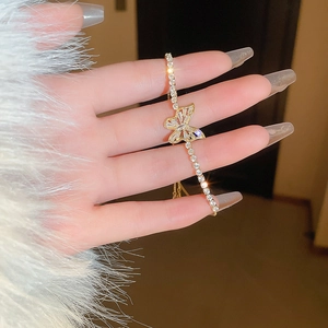 Elegant gold butterfly bracelet with zircons worn over a white faux fur sleeve