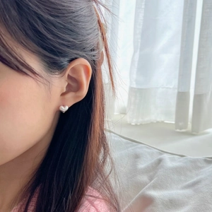 Close-up of minimalist brushed silver heart stud earring worn on model's ear
