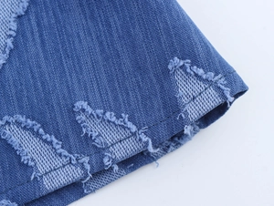 Close-up of blue denim fabric showing detailed twill texture and raw fringe edges