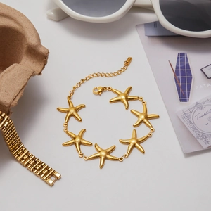 Macro shot of 18K gold starfish link bracelet with matte texture and lobster clasp
