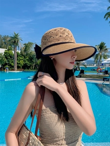 Detail of hollow woven sun hat with black trim and elegant side bow decoration