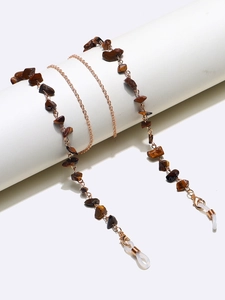 Close-up of golden chain for glasses with natural tiger eye stones and white silicone loops