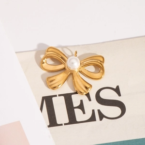 Detail of a golden bow pendant featuring a white pearl inlay on a stylized background