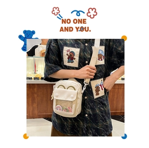 Detail of cute beige ita bag with transparent PVC layer for badge display and bear patches