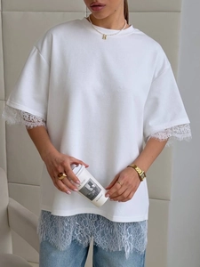 Detailed view of white cotton T-shirt featuring delicate lace trim on sleeves and hemline