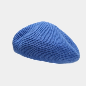 Close-up of thick blue wool knitted beret showing detailed diagonal ribbed texture
