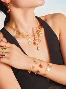 Close-up of gold titanium jewelry set featuring colorful clover and heart charms on model