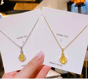 Detail of yellow teardrop zircon perfume bottle pendants in gold and silver finishes