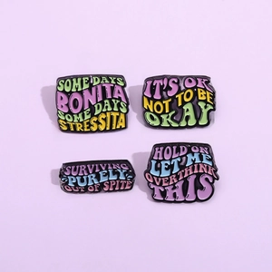 Set of four colorful enamel pins with fun English quotes on a minimalist purple background