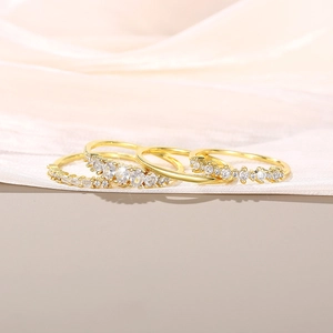 Detailopname van drie gouden ringen met zirkonia op een roze zijden stof