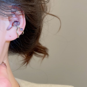 Macro side view of silver ear cuff with purple zircon stones on a model's ear