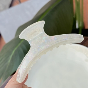 Close-up of large iridescent white acetate hair claw clip with glossy pearlescent finish