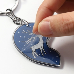 Acrylic heart keychain with white deer and night sky pattern featuring a protective film